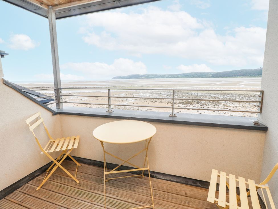 A balcony with a table and chairs overlooking the beach at 2 The Quay Pentraeth
