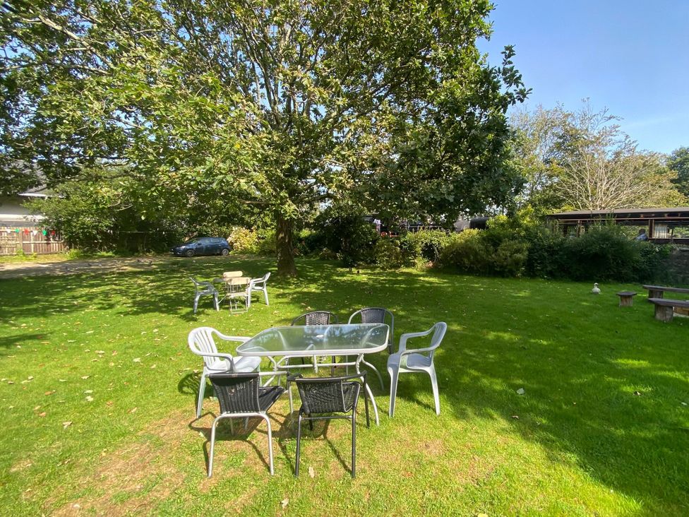 A garden with a table and chairs under a tree at Garden Flat Porthmadog
