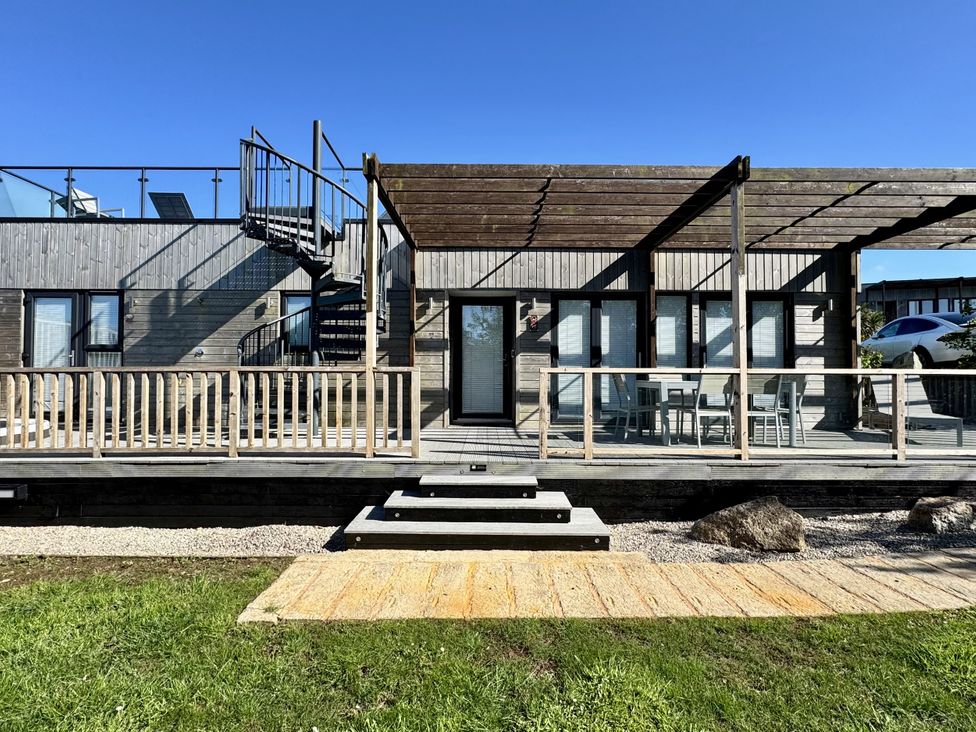 An outdoor view of a wooden deck with stairs and seating at The Black Barnacle Portreath