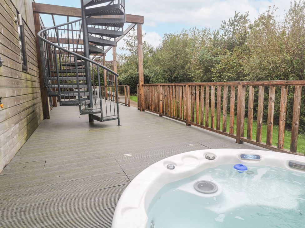 A hot tub on a deck with a spiral staircase at The Black Barnacle Portreath