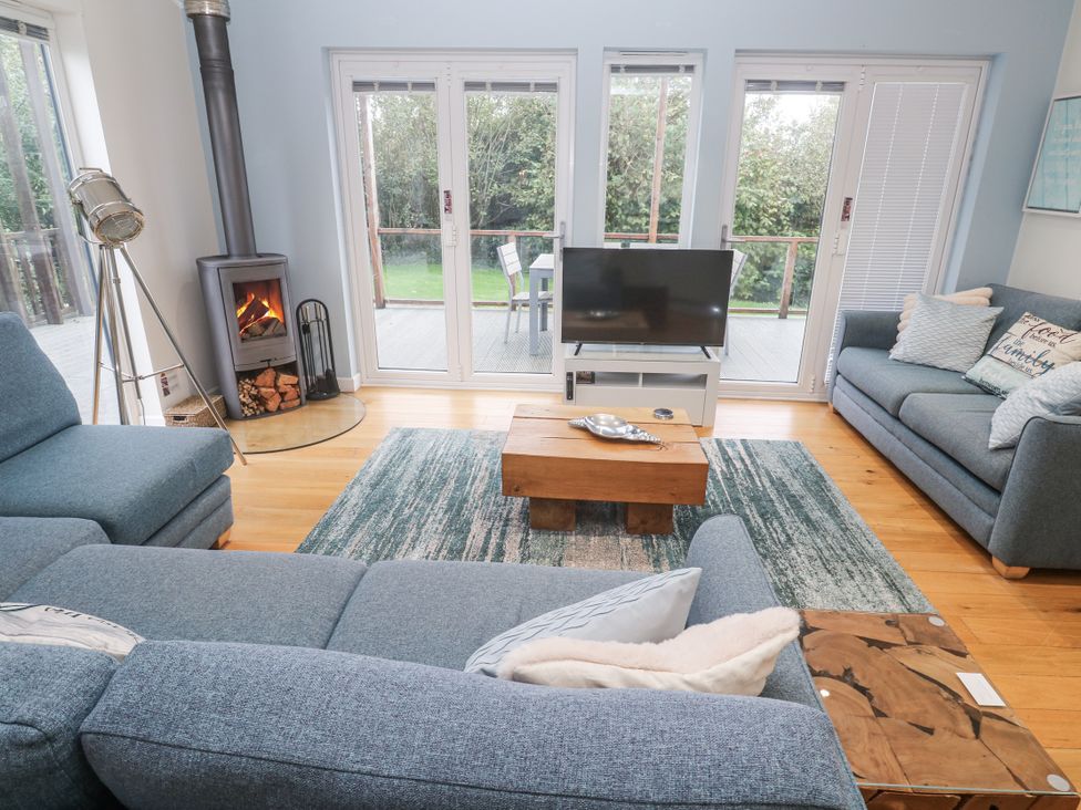 A living room with a fireplace and sliding doors at The Black Barnacle in Portreath