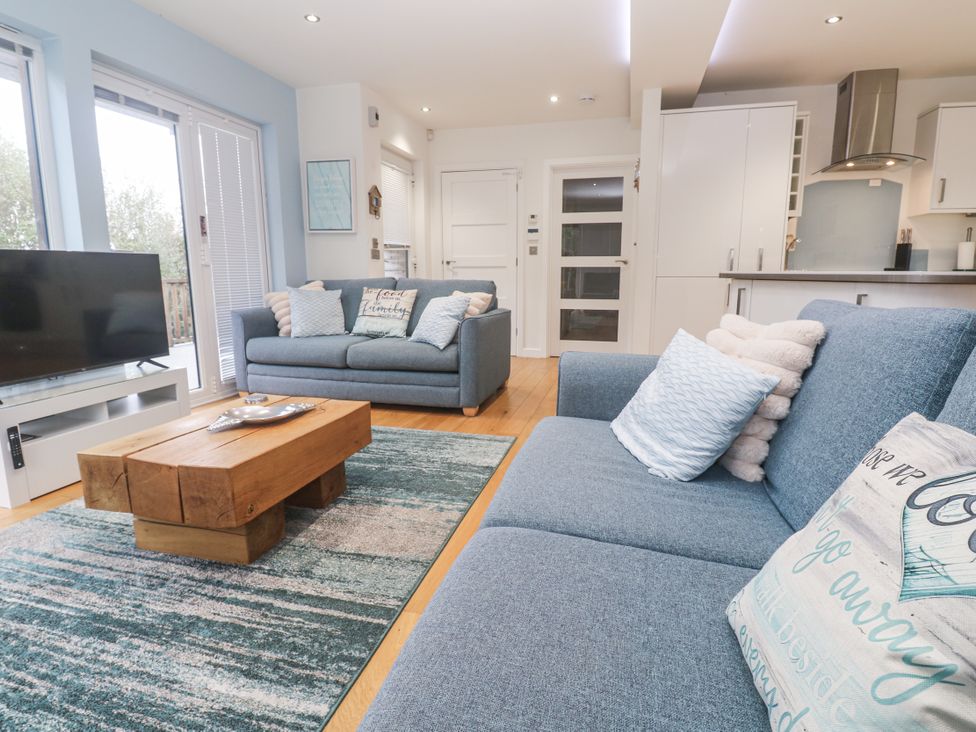 A living room with a sofa, coffee table, and television at The Black Barnacle in Portreath
