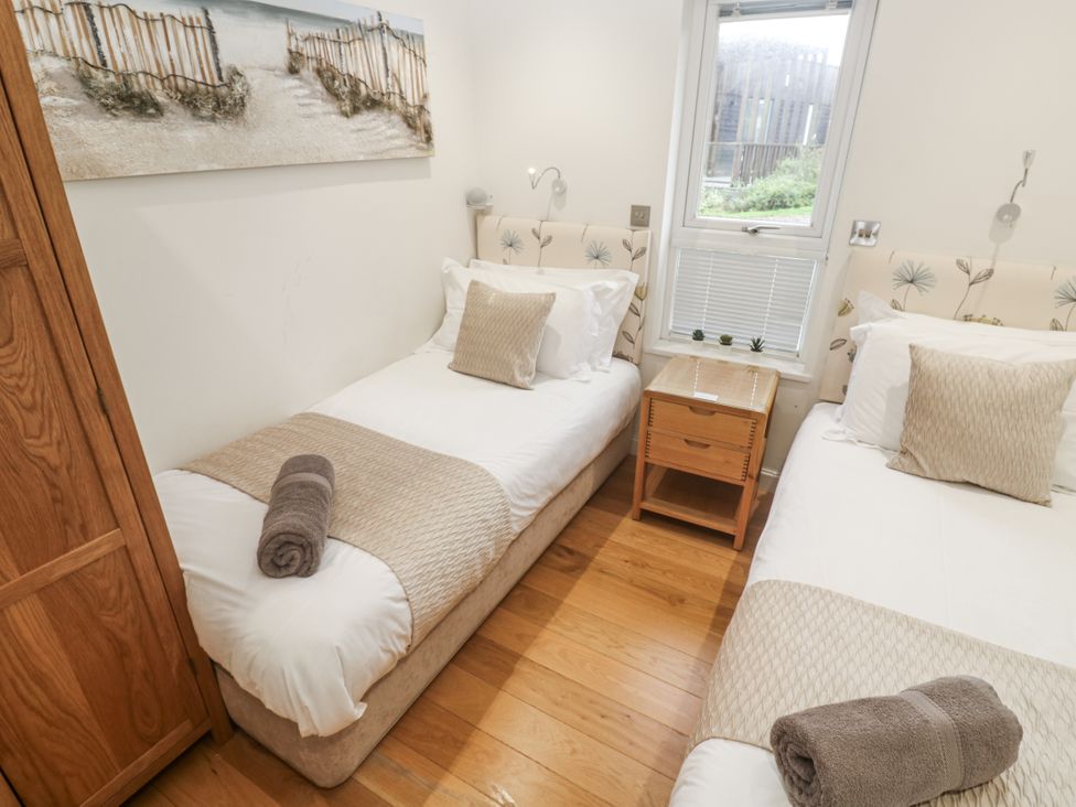 A bedroom with twin beds, a nightstand, and a window at The Black Barnacle Portreath