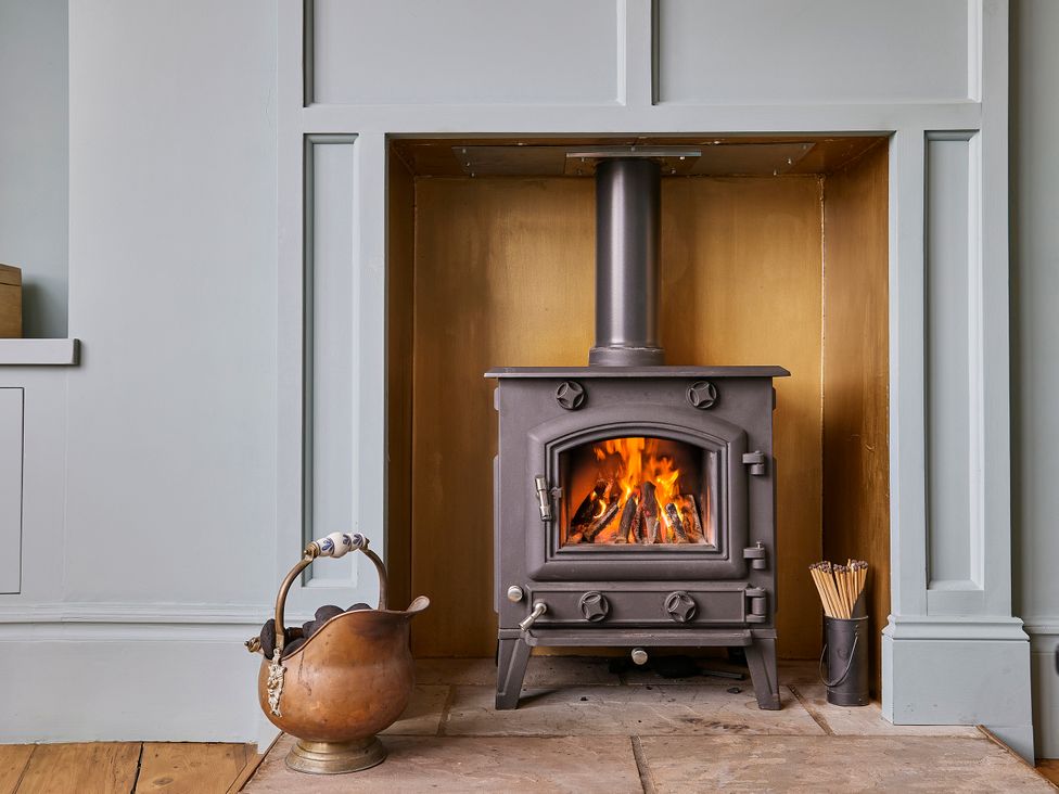 A living room with a wood stove and firewood at Isla House in Whitby
