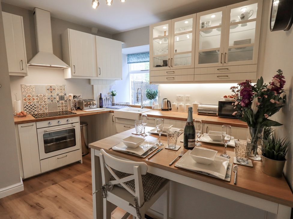 A kitchen with dishes and glasses set on a table at Olive Cottage in Kirkby Stephen