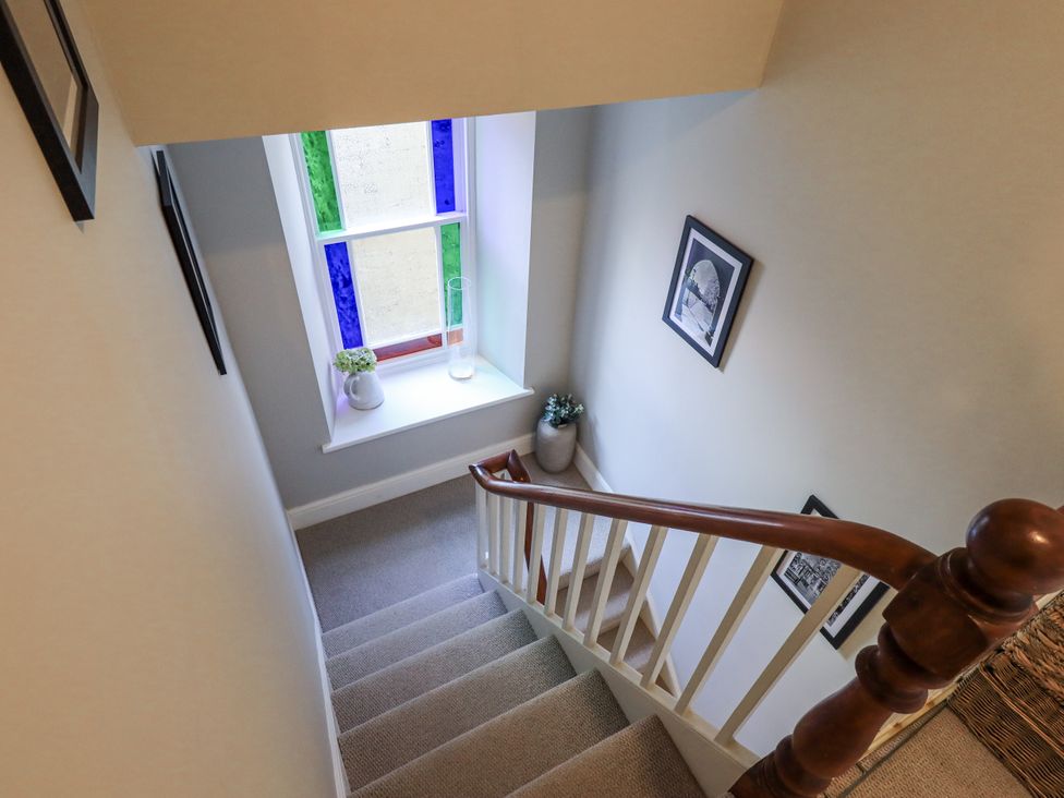 A stairway with a window and photographs at Olive Cottage in Kirkby Stephen