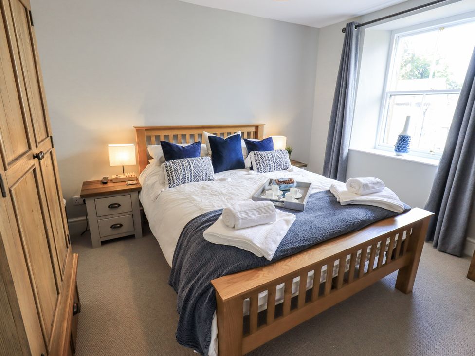 A bedroom with a bed, wardrobe, and bedside table at Olive Cottage in Kirkby Stephen
