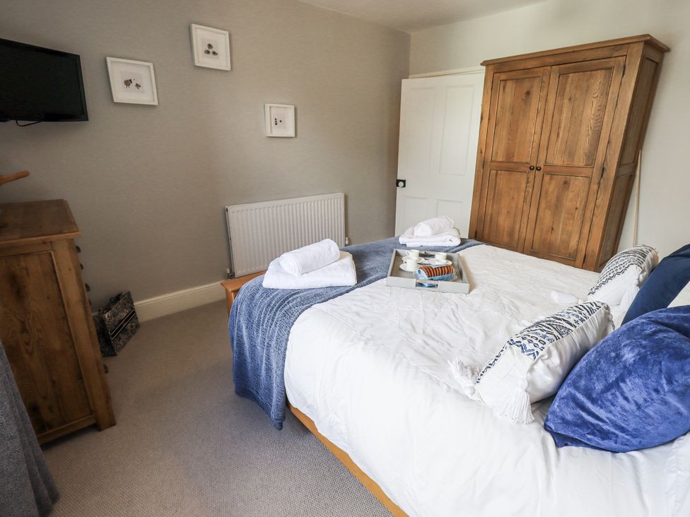 A bedroom with a bed and wardrobe at Olive Cottage in Kirkby Stephen