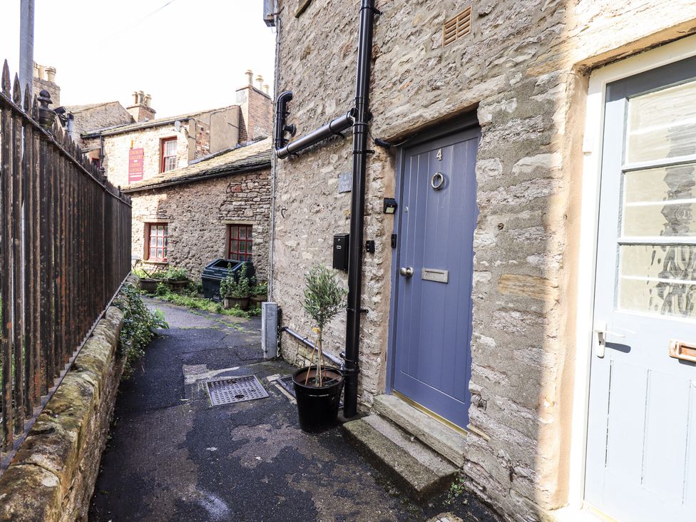 An outdoor area with a blue door and a window at Olive Cottage in Kirkby Stephen