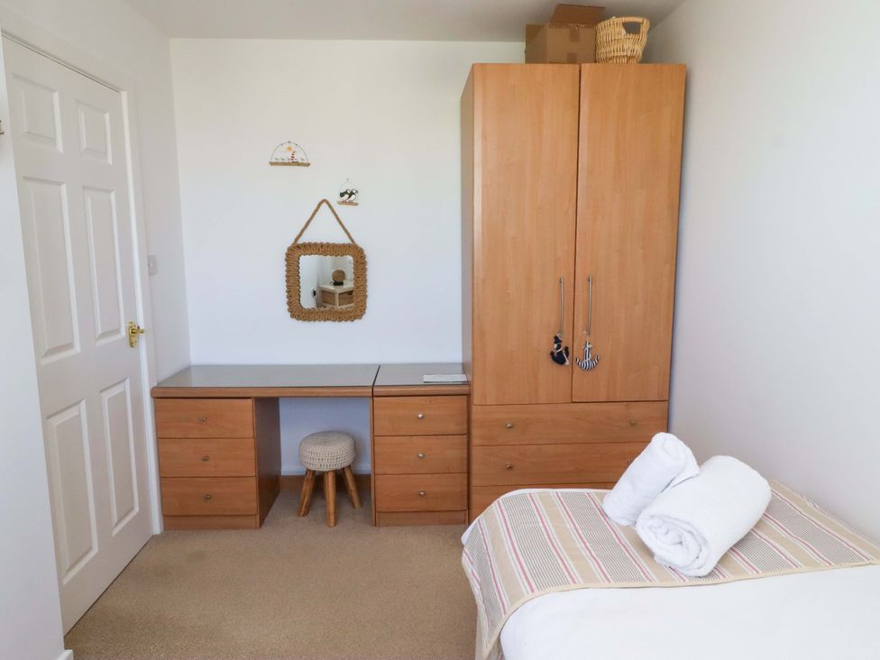 A bedroom with a wardrobe, desk, and towels at Sea Shore in Seahouses