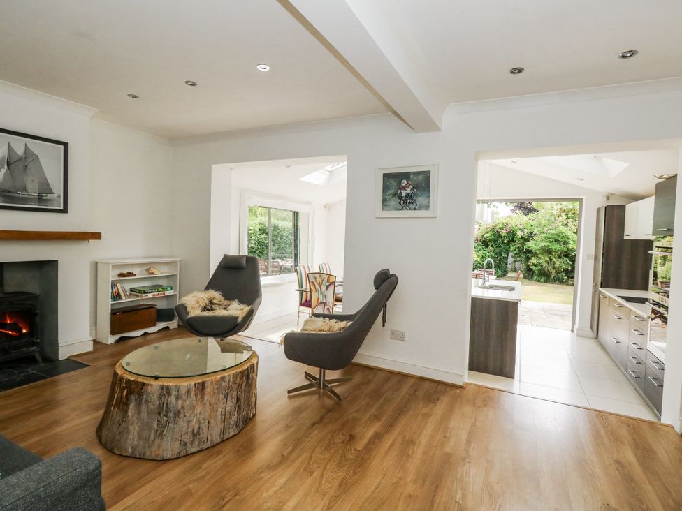A living room with a fireplace and a view of the kitchen at King Henry House in Lymington