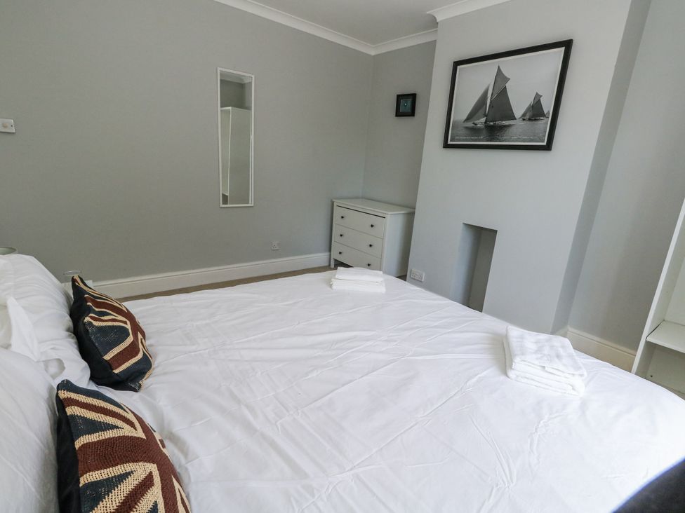 A bedroom with a bed, chest of drawers, and a mirror at King Henry House in Lymington