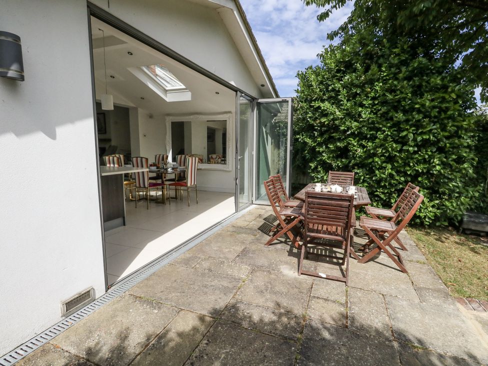 A garden with a wooden dining set and sliding doors at King Henry House in Lymington