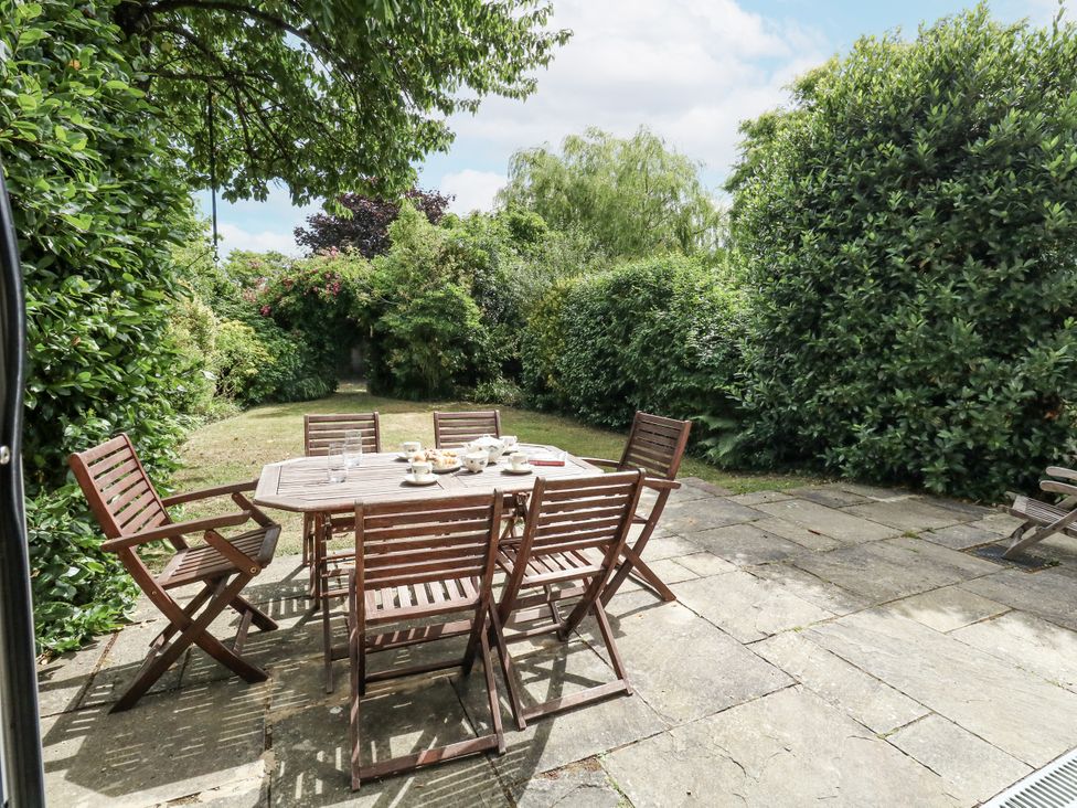 A garden with a wooden table and chairs at King Henry House in Lymington