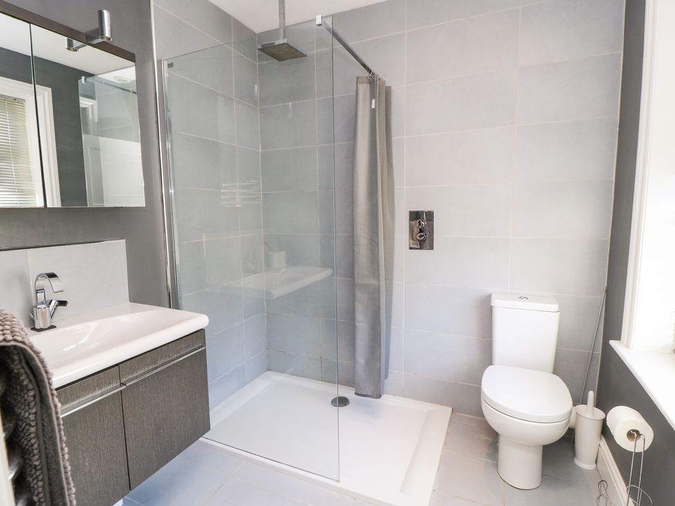 A bathroom with a shower, toilet, sink, and mirror at King Henry House in Lymington