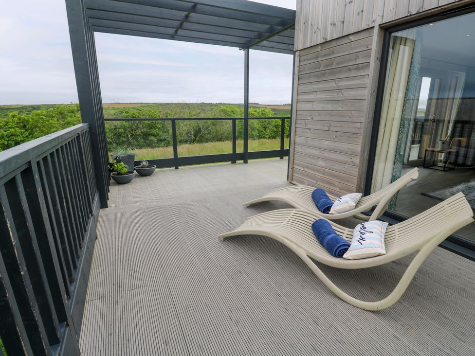 An outdoor terrace with two sun loungers and potted plants at Dahlia in Portreath