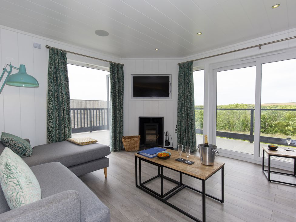 A living room with a sofa and television at Dahlia in Portreath