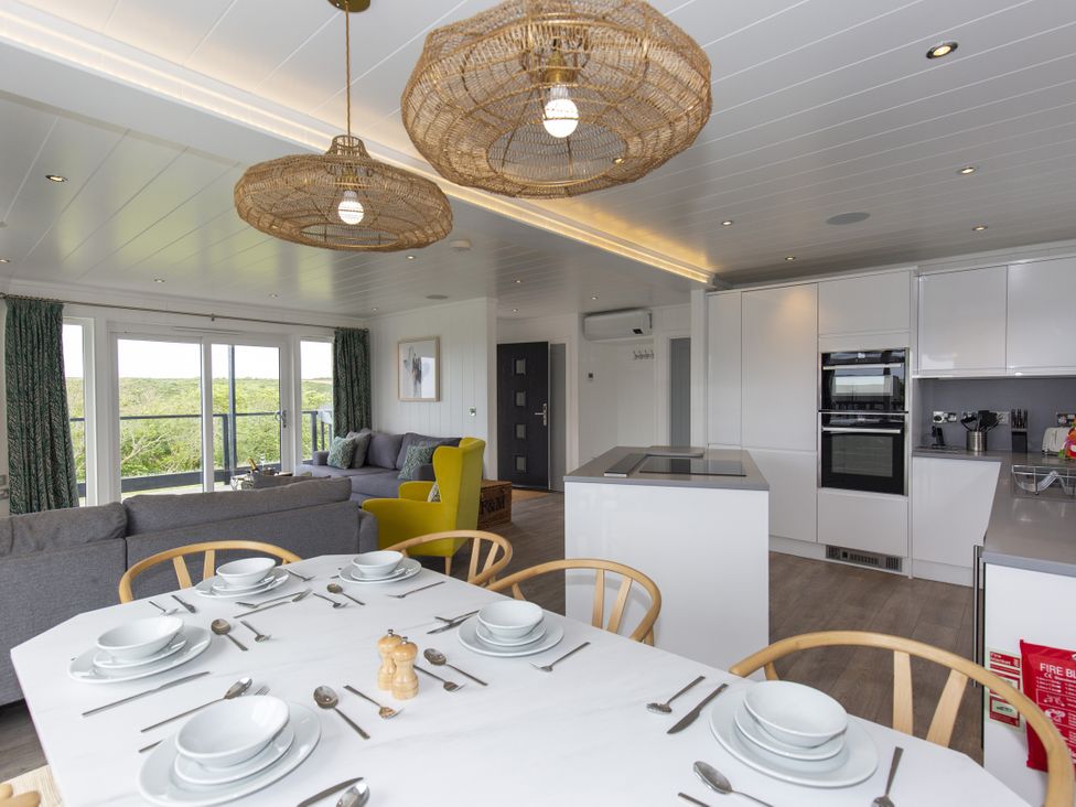 A dining room with a table set for meals at Dahlia in Portreath