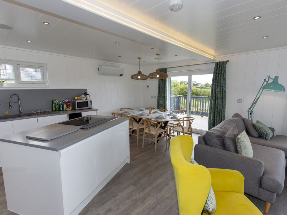 A living room with a kitchen island and dining area at Dahlia in Portreath