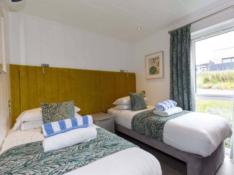 A bedroom with two beds and a window at Dahlia in Portreath