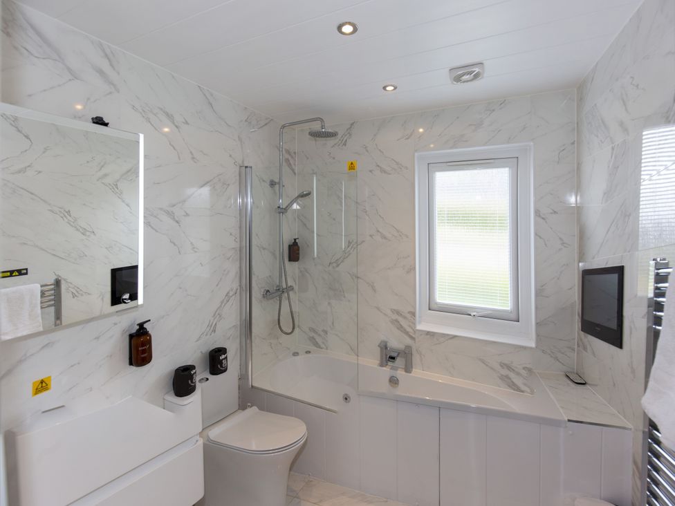 A bathroom with a shower and bathtub at Dahlia in Portreath