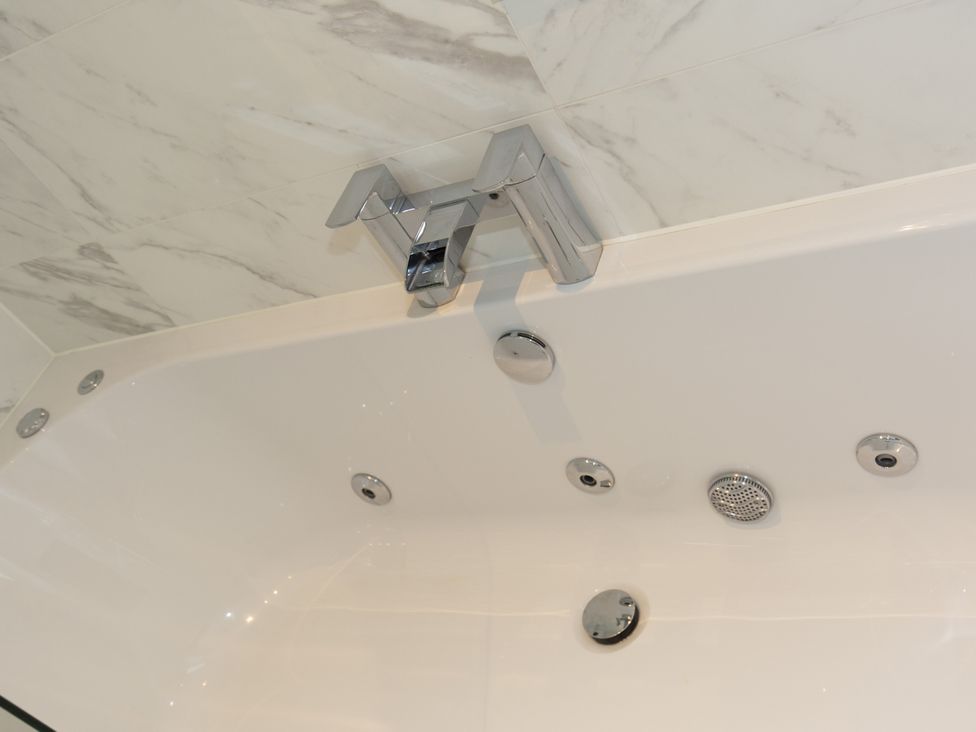 A bath tub with a faucet and water jets at Dahlia in Portreath