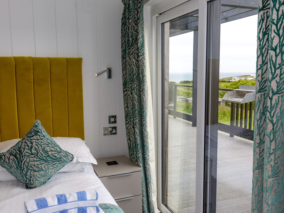 A bedroom with a bed and outdoor view at Dahlia in Portreath