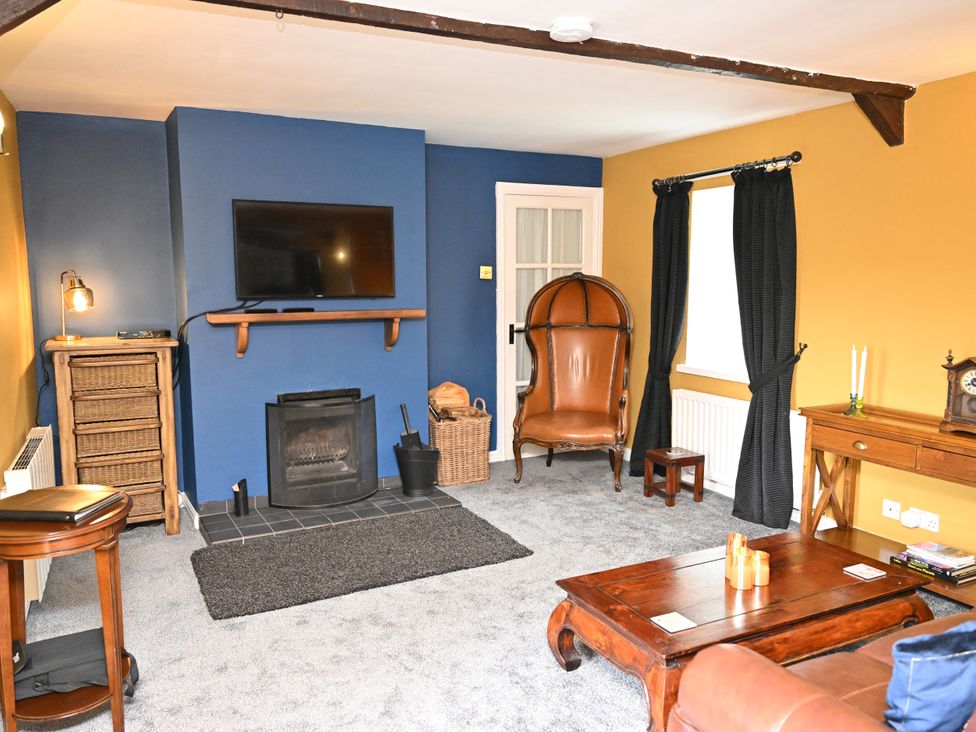 A living room with a television and fireplace at Petty Knowes Cottage Rochester near Otterburn