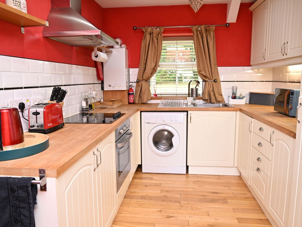 A kitchen with wooden cabinets and appliances at Petty Knowes Cottage Rochester near Otterburn