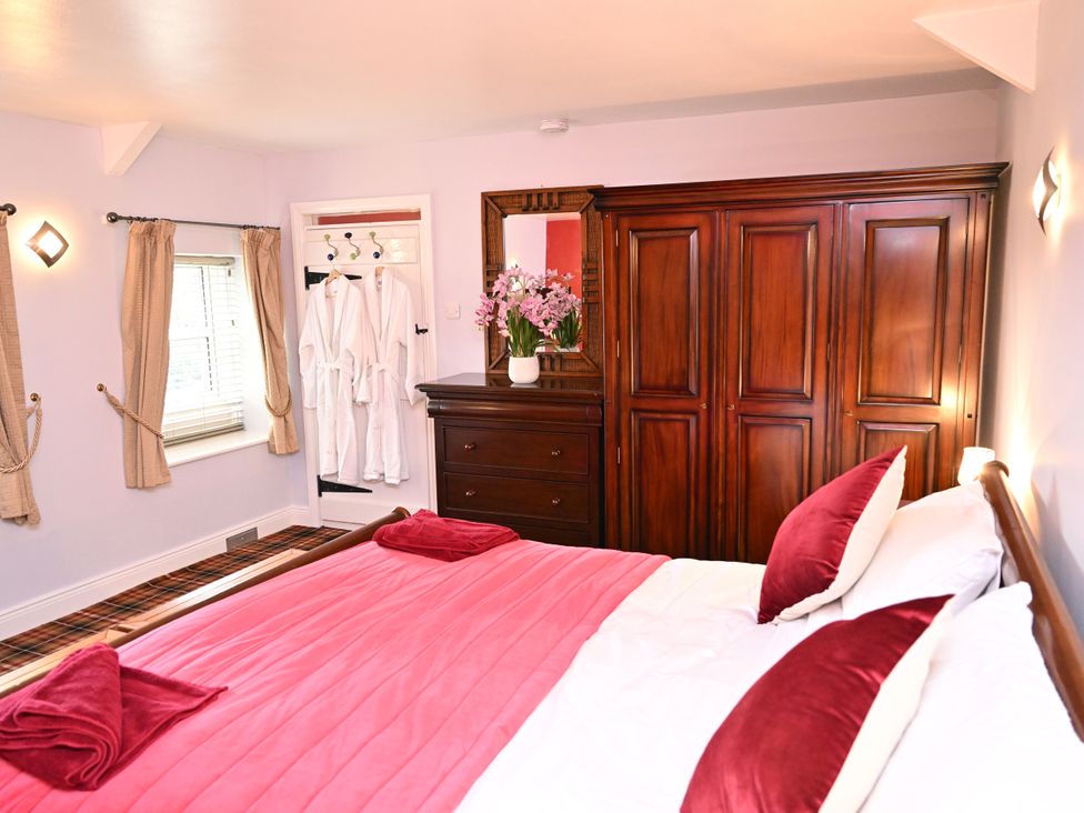 A bedroom with a bed and dresser at Petty Knowes Cottage Rochester near Otterburn