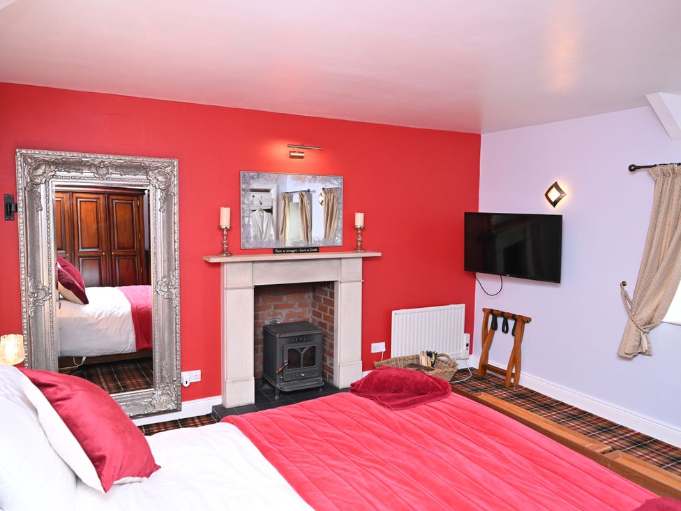 A bedroom with a bed and fireplace at Petty Knowes Cottage Rochester near Otterburn
