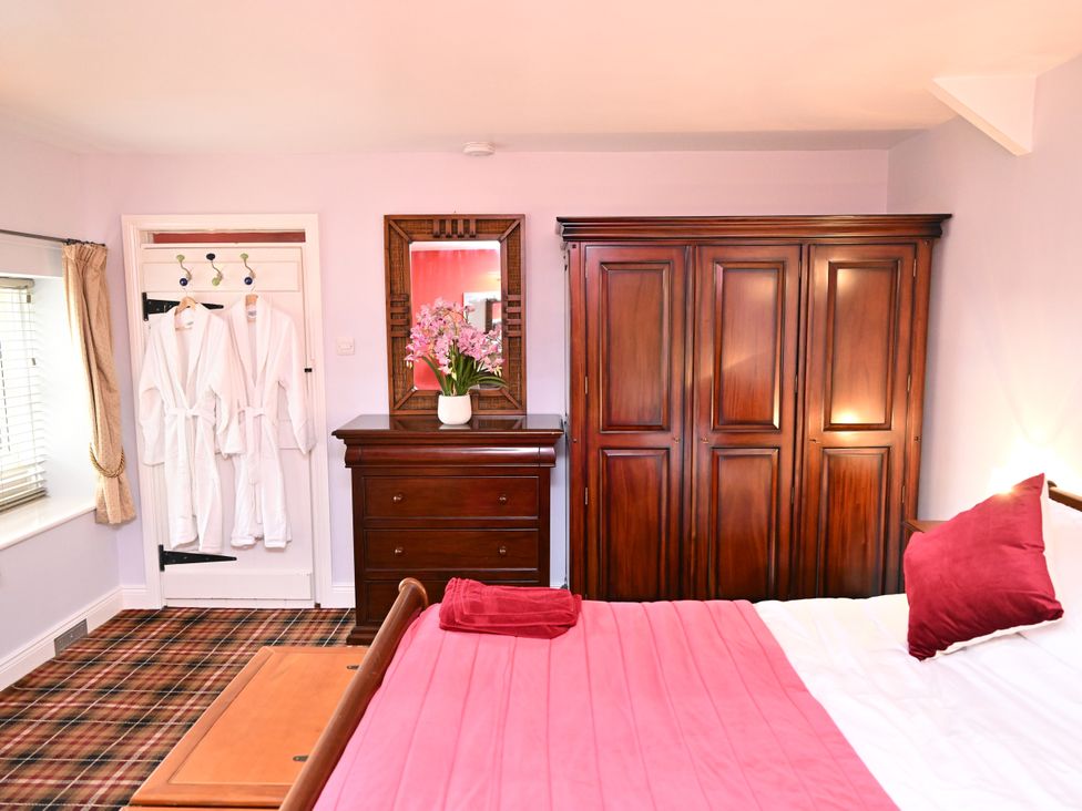 A bedroom with a bed and wooden furnishings at Petty Knowes Cottage Rochester near Otterburn