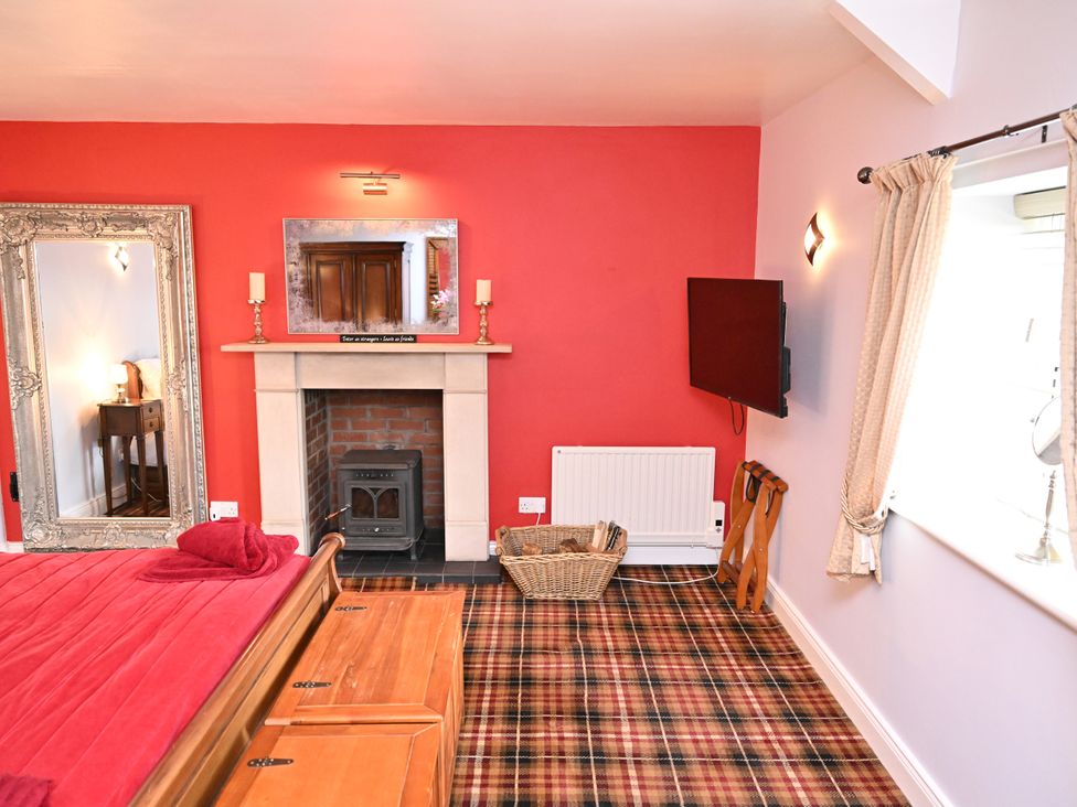 A bedroom with a bed, fireplace and television at Petty Knowes Cottage Rochester near Otterburn