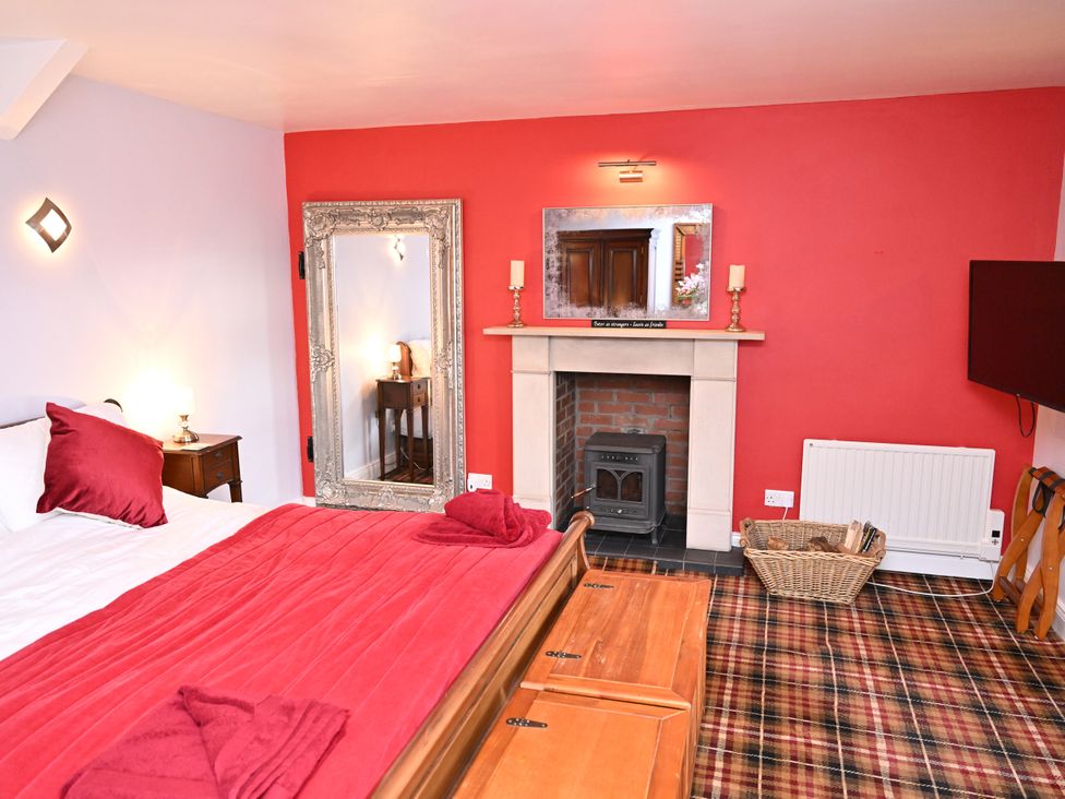 A bedroom with a bed and fireplace at Petty Knowes Cottage Rochester near Otterburn