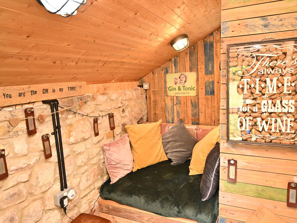 A snug area with stone walls and a sofa at Petty Knowes Cottage in Rochester near Otterburn