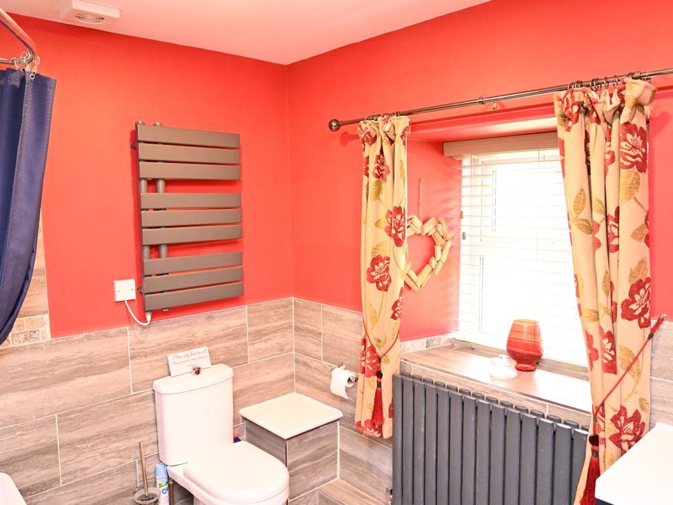 A bathroom with a toilet and a radiator at Petty Knowes Cottage Rochester near Otterburn