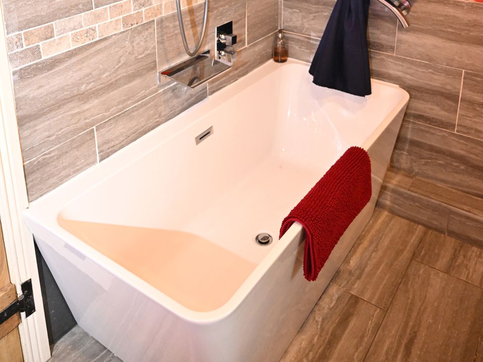 A bathtub with a red towel at Petty Knowes Cottage Rochester near Otterburn