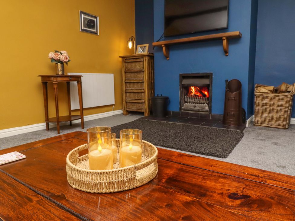 A living room with a fireplace and candles at Petty Knowes Cottage Rochester near Otterburn
