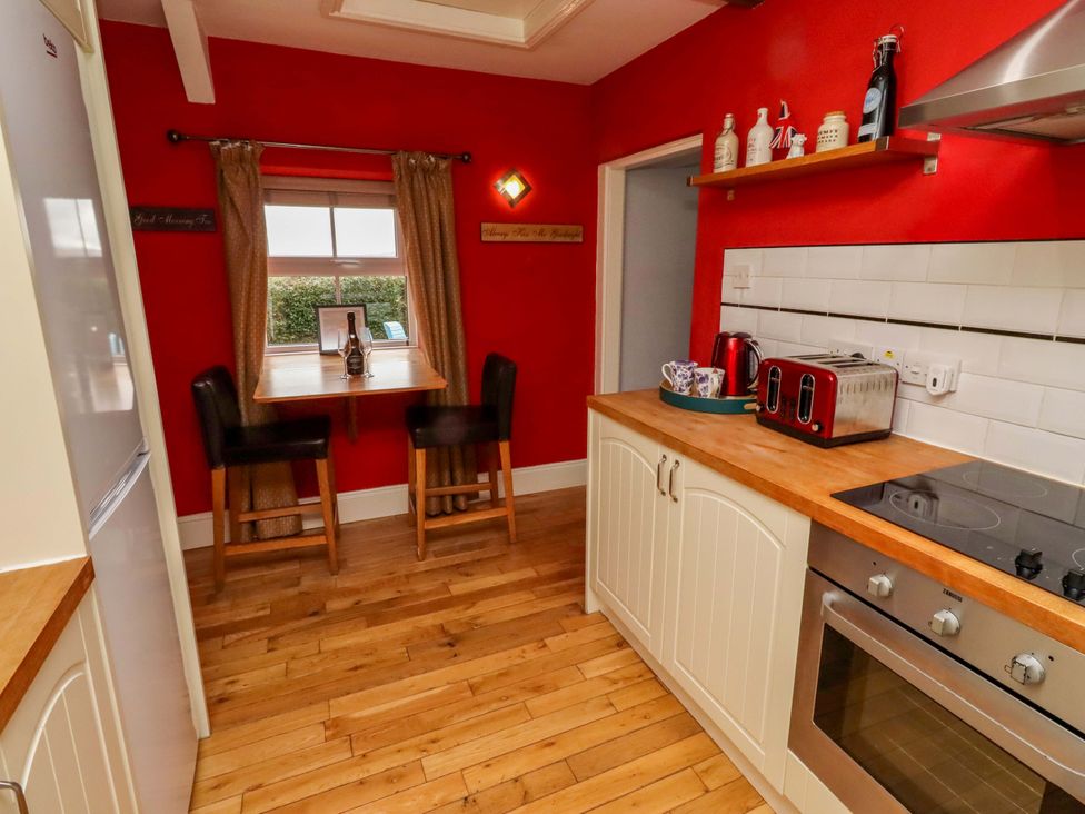 A kitchen with a table and stools at Petty Knowes Cottage Rochester near Otterburn