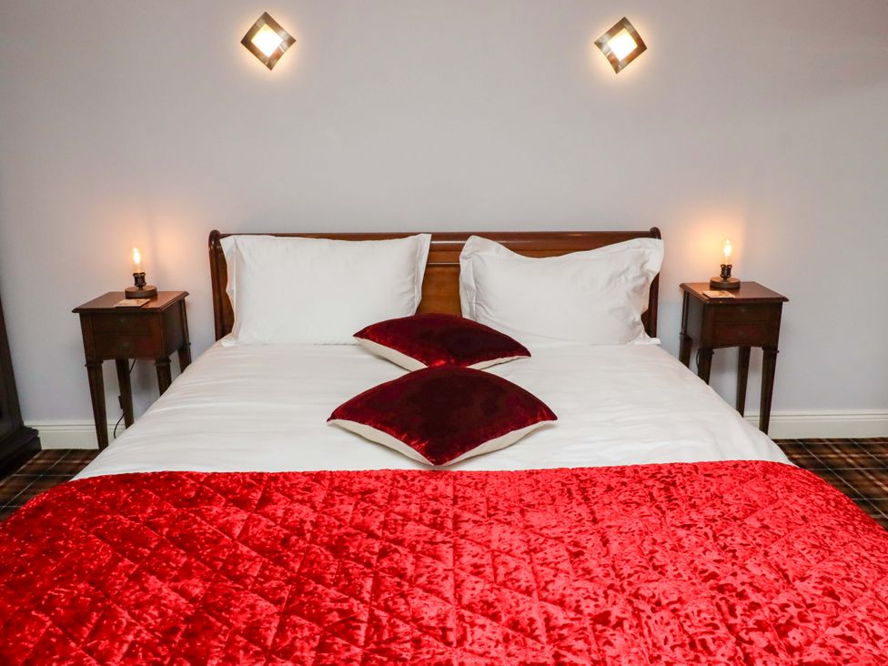 A bedroom with a bed and bedside tables at Petty Knowes Cottage Rochester near Otterburn