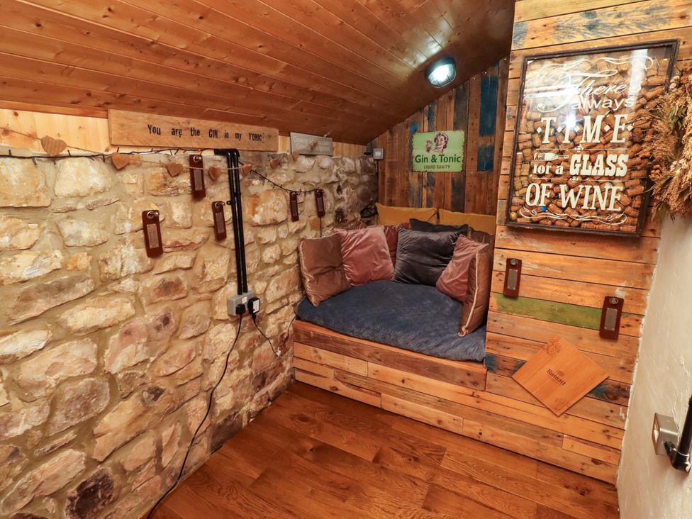 A snug area with a built-in couch and wooden walls at Petty Knowes Cottage in Rochester near Otterburn