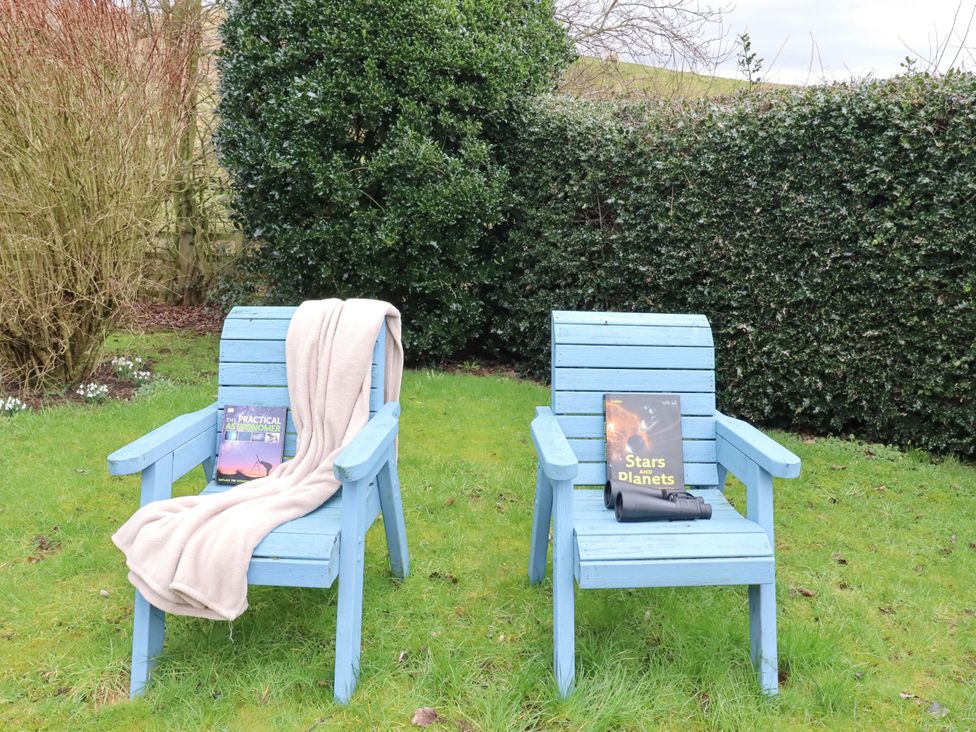 Two blue chairs with books and a telescope in the garden at Petty Knowes Cottage Rochester near Otterburn