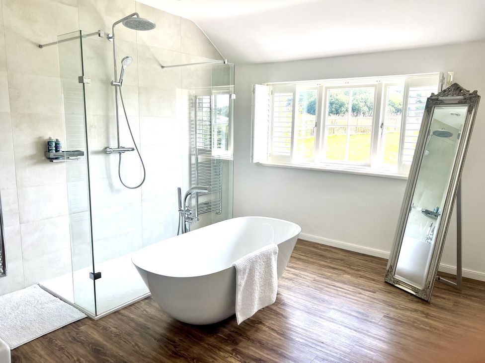 A bathroom with a bathtub and shower at Higher Park Farm in Alderley Edge