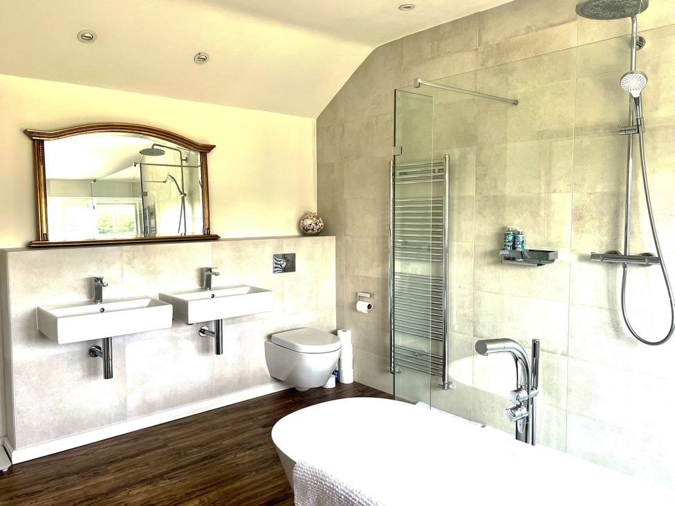 A bathroom with sinks, a shower, and a bathtub at Higher Park Farm in Alderley Edge