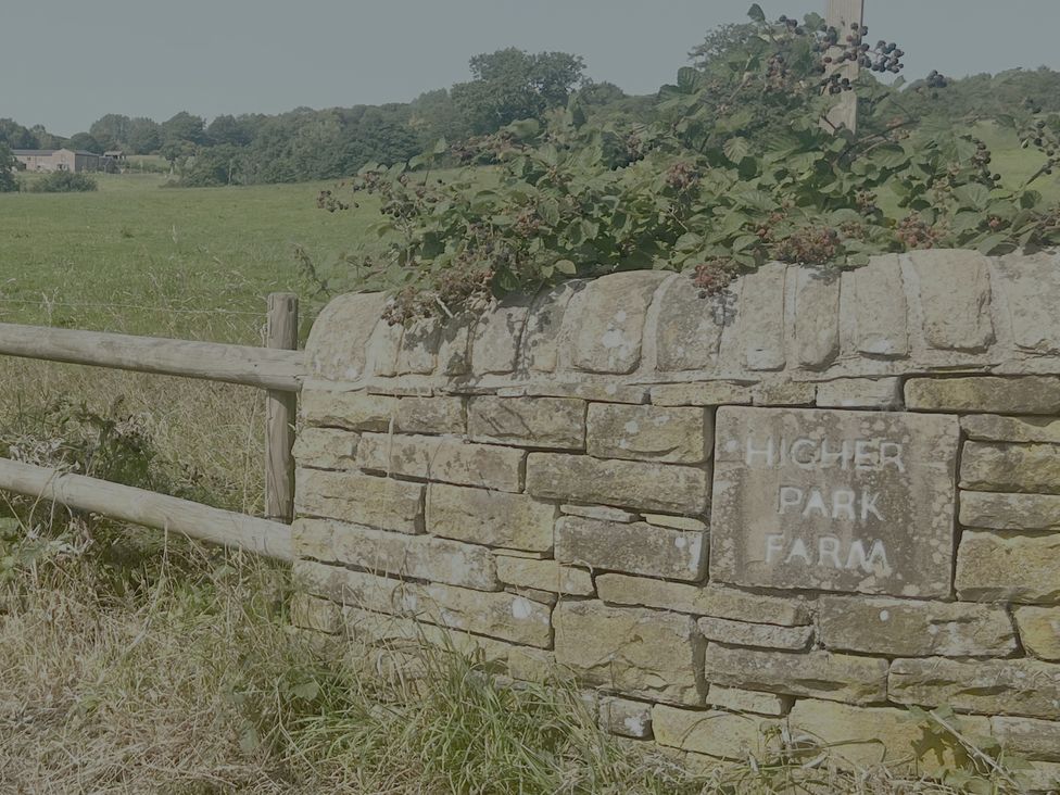 A stone wall with a farm sign at Higher Park Farm in Alderley Edge