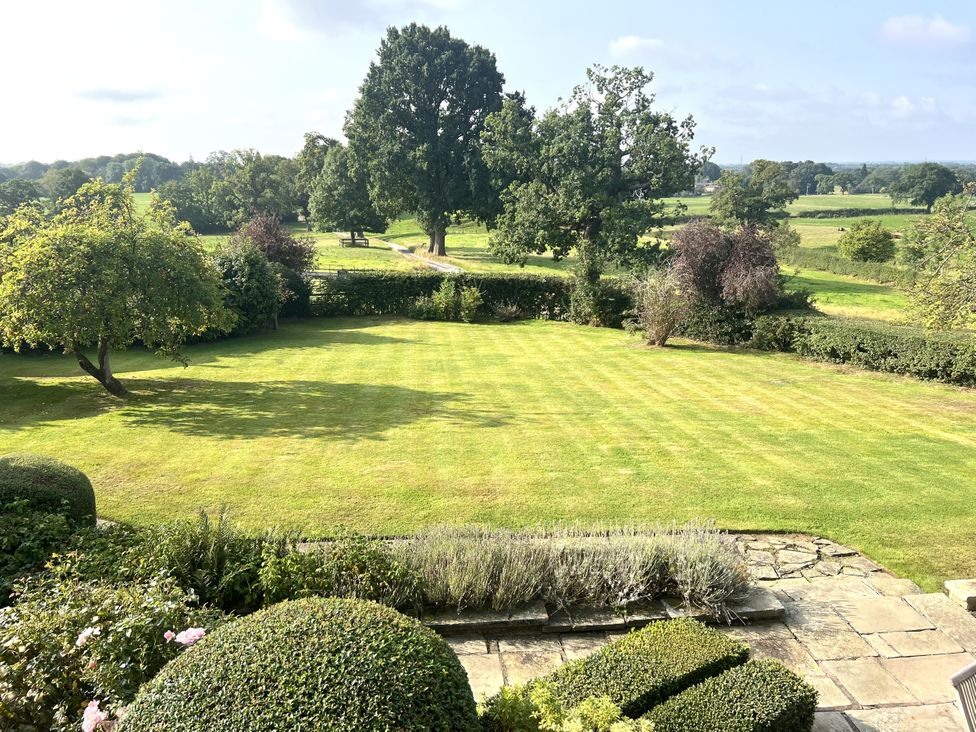 A garden with grass, trees, and hedges at Higher Park Farm in Alderley Edge