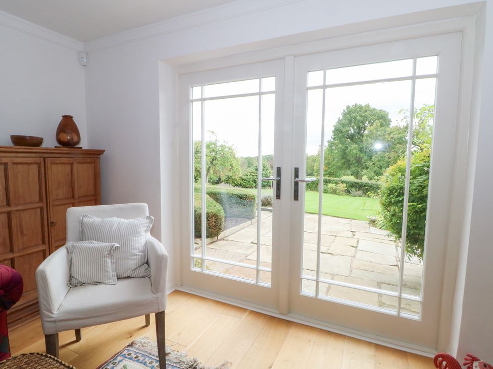 A living room with double doors and a chair at Higher Park Farm in Alderley Edge