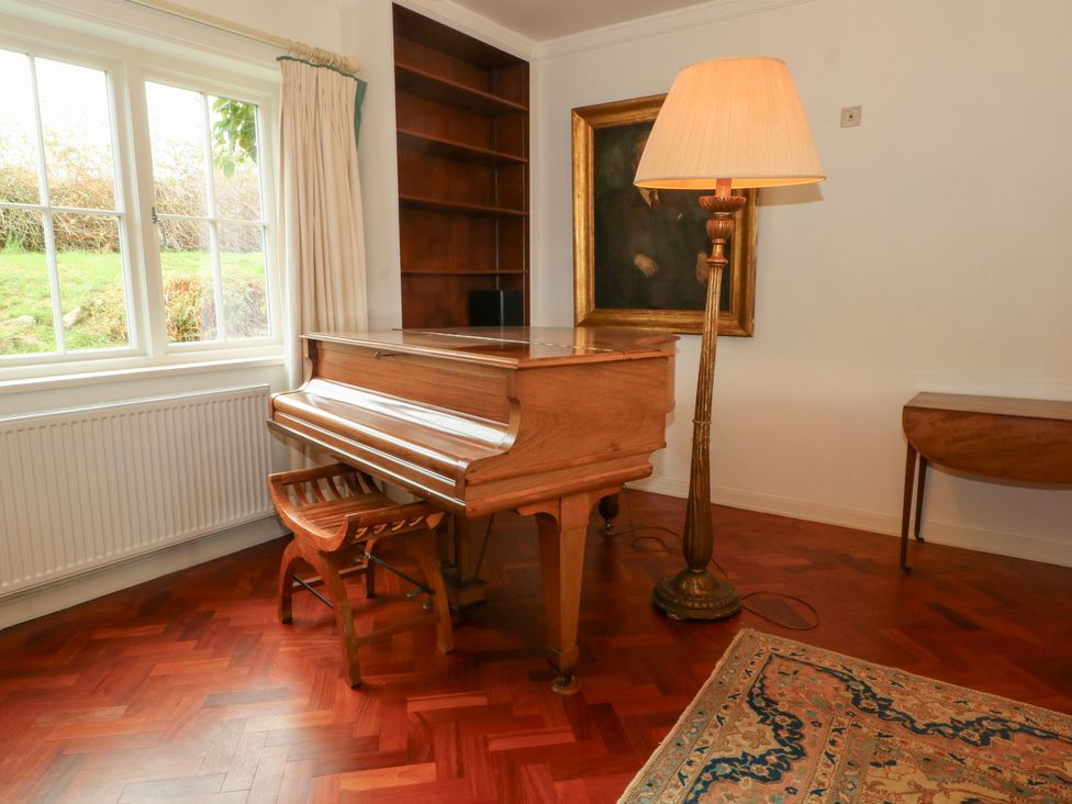 A living room with a piano and lamp at Higher Park Farm in Alderley Edge