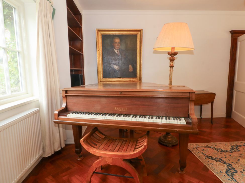 A living room featuring a piano with a lamp and a painting at Higher Park Farm in Alderley Edge