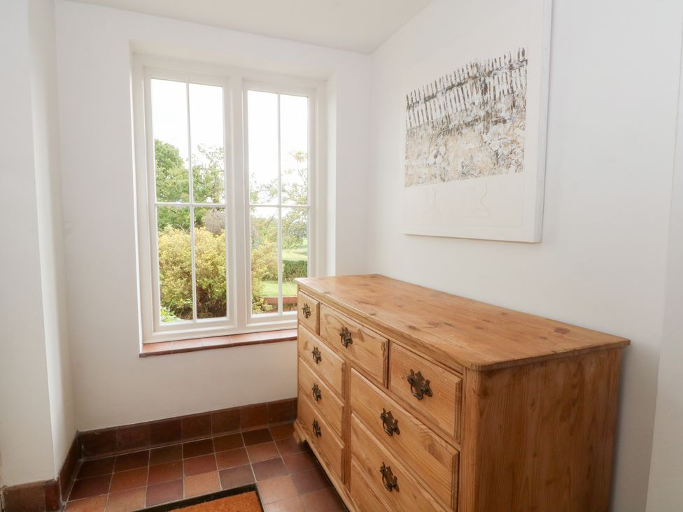 A hallway with a dresser and window at Higher Park Farm in Alderley Edge